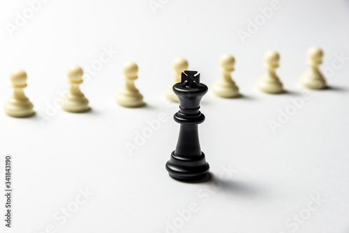 chess king is standing against white pawns. Symbol of leadership and confrontation. Horizontal frame