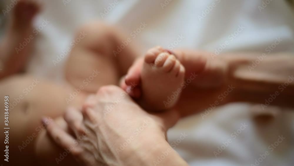 Mom pats the leg of newborn. Woman doing foot massage to baby. Close up. Mom pats the leg of newborn. Woman doing foot massage to baby. Close up.