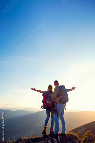 Hikers with backpacks relaxing on top of a mountain and enjoying the view of valley