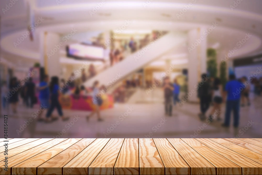 Empty wooden table with blurred shopping mall background.