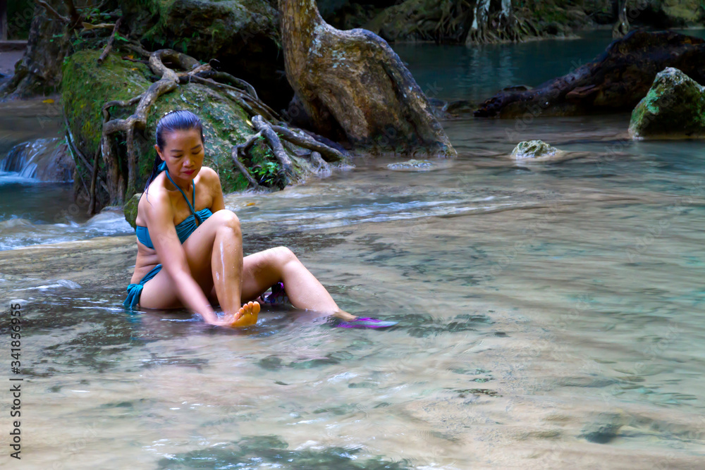 Fototapeta premium Woman in blue swimsuit sit happy at Erawan Waterfall
