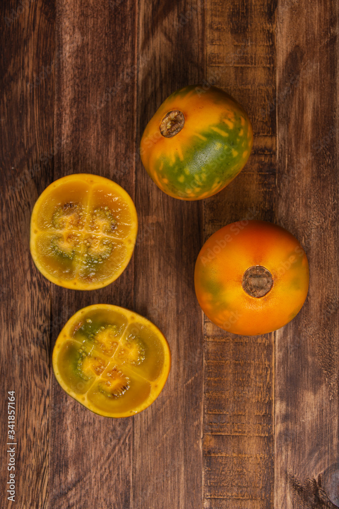 Organic lulo or naranjilla south america exotic fruit. Top view of fruits on old table and dark background. Solanum quitoense, dark food