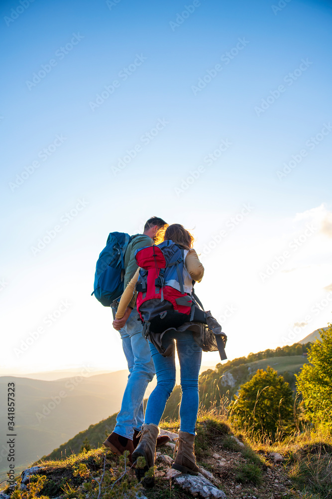 Hikers with backpacks relaxing on top of a mountain and enjoying the view of valley