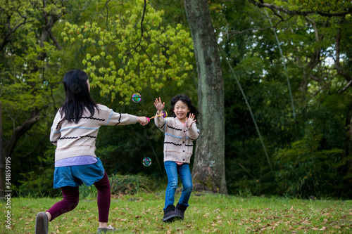 公園でしゃぼん玉を遊んでいる子供姉妹