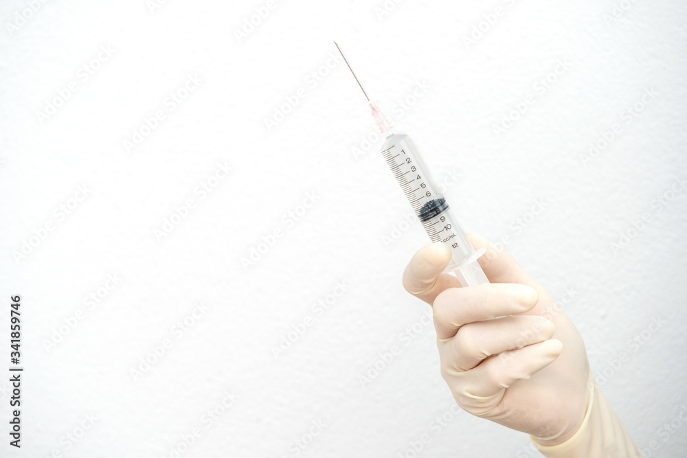 Close up of Nurse/Doctor hand holding a plastic Syringe, medical injection in hand. A syringe is a small tube with a thin hollow needle at the end. Syringes are used for putting liquids into things. Close up of Nurse/Doctor hand holding a plastic Syringe, medical injection in hand. A syringe is a small tube with a thin hollow needle at the end. Syringes are used for putting liquids into things.