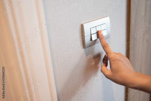 Close up of finger is turning on or off in light switch.