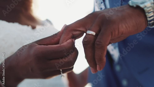 Front view of holding together hands just married afroamerican couple, with wedding bands, luxury man hand watch, engagement ring with huge diamond, in love