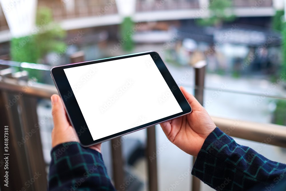 Mockup image of a woman holding black tablet pc with blank white desktop screen indoors Mockup image of a woman holding black tablet pc with blank white desktop screen indoors