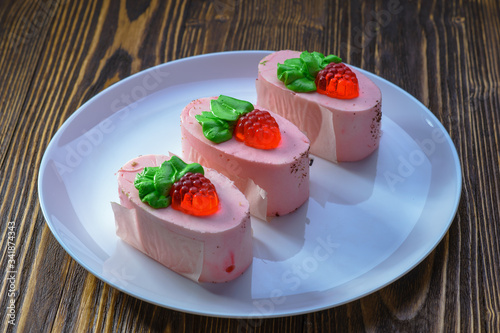 three tender pink cakes with red berries on a white dish