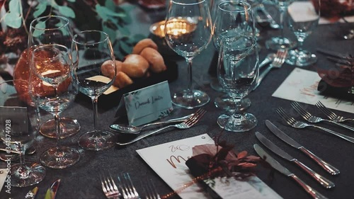Table serving with floral decorative composition and burning candles in the fashionable authentic luxury restaurant,tablet with guest names