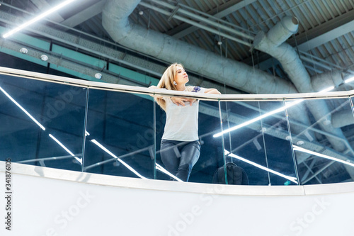 Beautiful blonde woman in a modern futuristic building on the balcony. View from below. © Анна Демидова