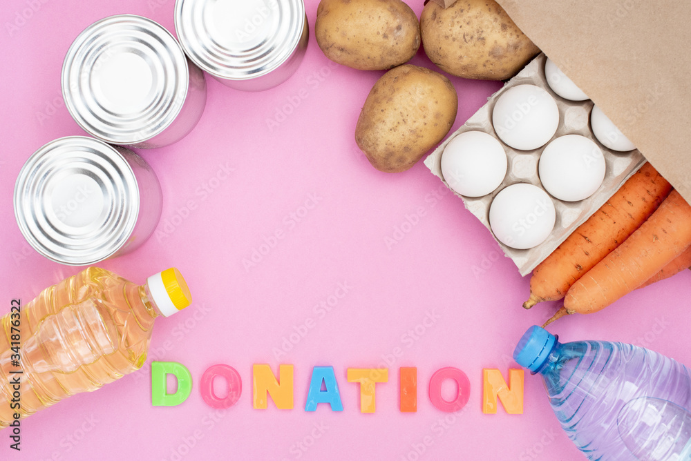 Food donation for the needy on a pink background top view. Potatoes, carrots, water, oil, eggs and canned food. Food donation for the needy on a pink background top view. Potatoes, carrots, water, oil, eggs and canned food.