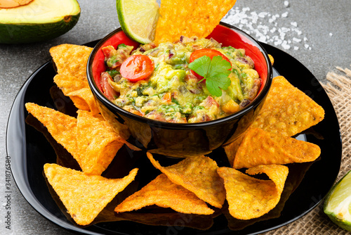 Guacamole with corn chips on a white stone background. Fast food.