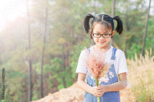 Happy smiling little girl holding wildflowers in her hands.