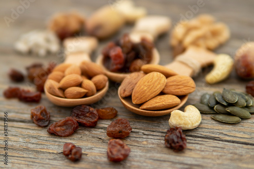 Almonds, apricot seed on a wooden spoons. Raisins, cashews, figs, nuts on top of a wooden board.