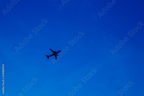 The silhouette of an airplane is climbing against a clear blue sky. Place for text or paste, copy place