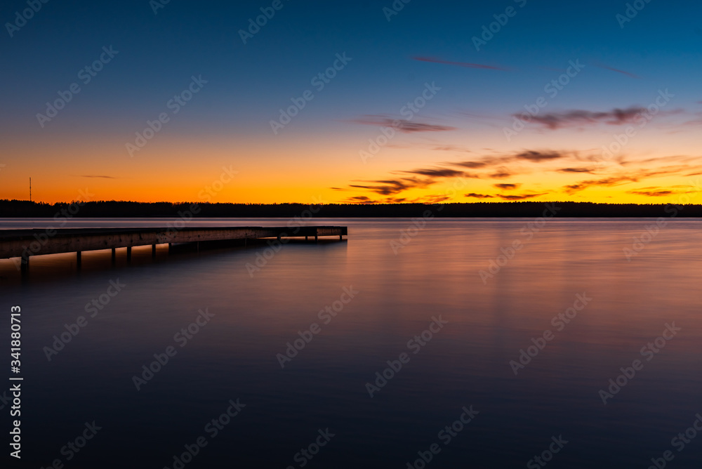 Sunset on the shore of the lake with a footbridge Sunset on the shore of the lake with a footbridge
