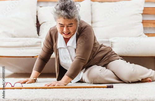 Asian senior woman falling down lying on floor at home alone. Elderly woman pain and hurt from osteoporosis sickness or heart attack. Old adult life insurance with hearlth care and treatment concept photo