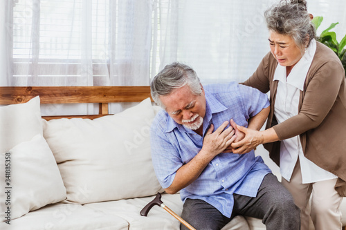 Retired Asian senior elderly husband pain from heart attack disease or illness with serious or worried wife take care at home. Medical emrgency treatment and health care insurance protection concept