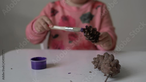 Toddler girl painting white table with purple paint. Creative child mess. Homeschooling.  photo