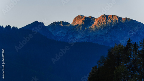 Beautiful panoramic sunrise view of mountain range with peaks. Austrian Alps. Postcard concept. Picture contains blue and orange colours.