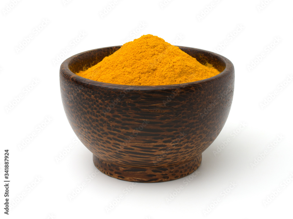 Turmeric (curcumin) powder in a black wooden bowl isolated on a white background. Turmeric (curcumin) powder in a black wooden bowl isolated on a white background.
