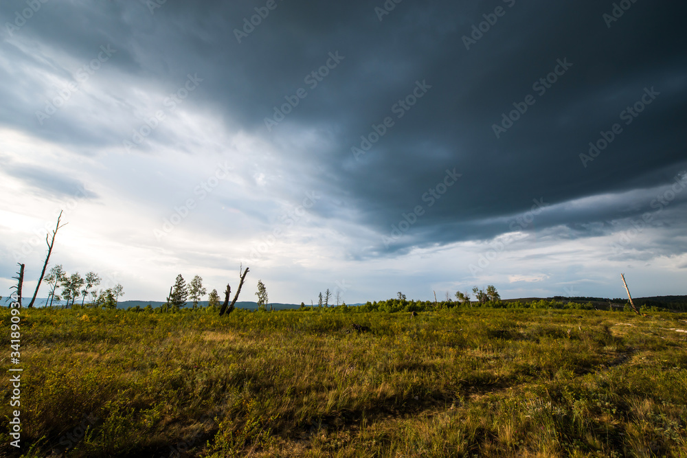 small mountains, illuminated by the setting sun, and storm clouds in the sky small mountains, illuminated by the setting sun, and storm clouds in the sky
