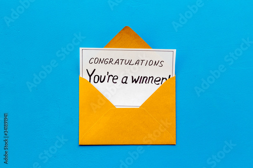 You're a winner. Envelope with congratulation card on blue table top view