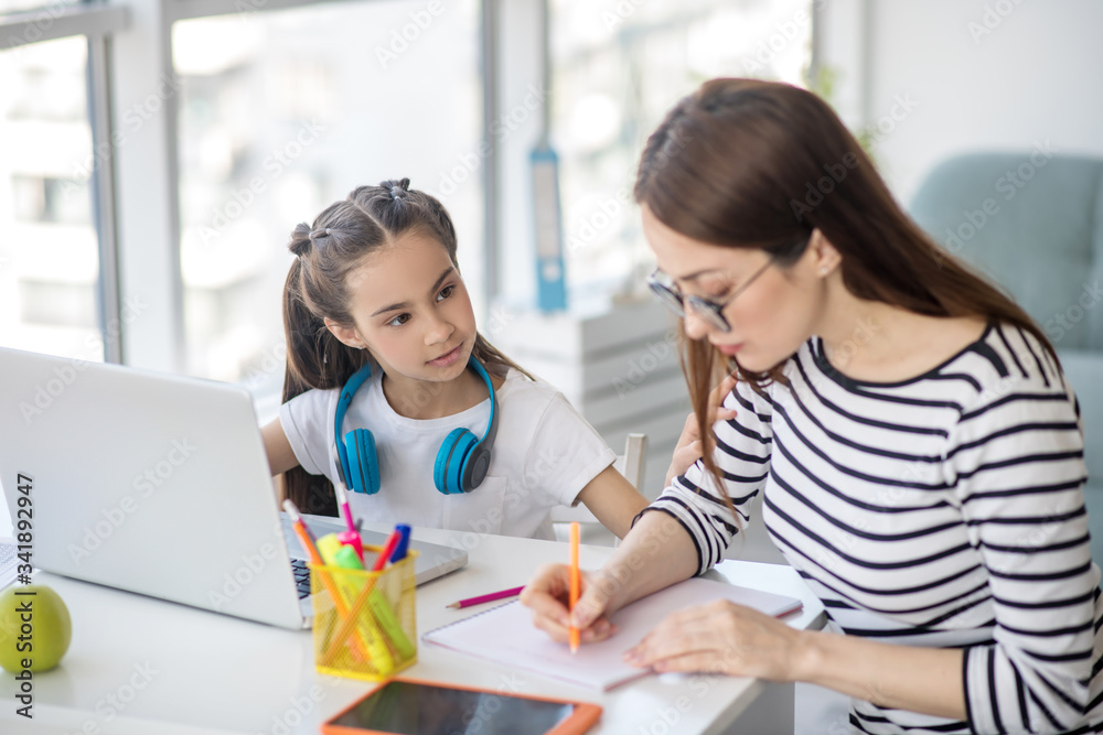 Working at home mother and school daughter at table. Working at home mother and school daughter at table.