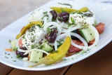 Griechischer Bauernsalat mit Oliven, Peperoni, Feta, Gurke, Tomate und Zwiebeln auf Holz Tisch