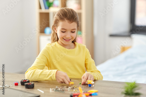 children, technology and science concept - happy girl playing with robotics kit at home