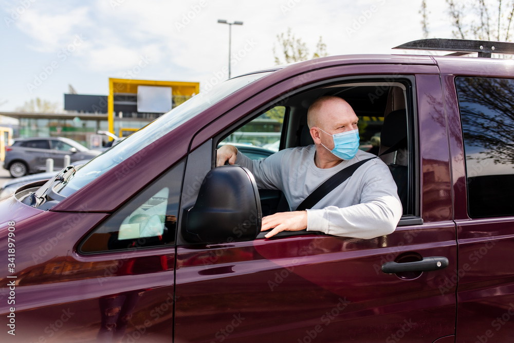A man in a protective mask driving a car. Portrait of a man in a car in a surgical mask. A man goes to rest in the countryside. A man in a protective mask driving a car. Portrait of a man in a car in a surgical mask. A man goes to rest in the countryside.