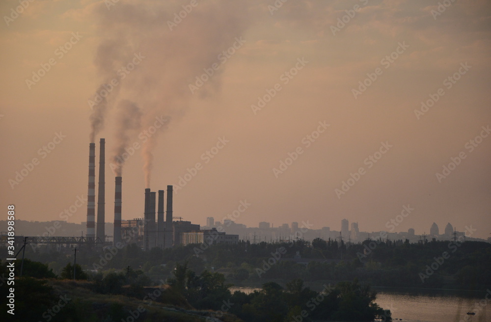 silhouette of an old smoking thermal power plant working on coal at sunset