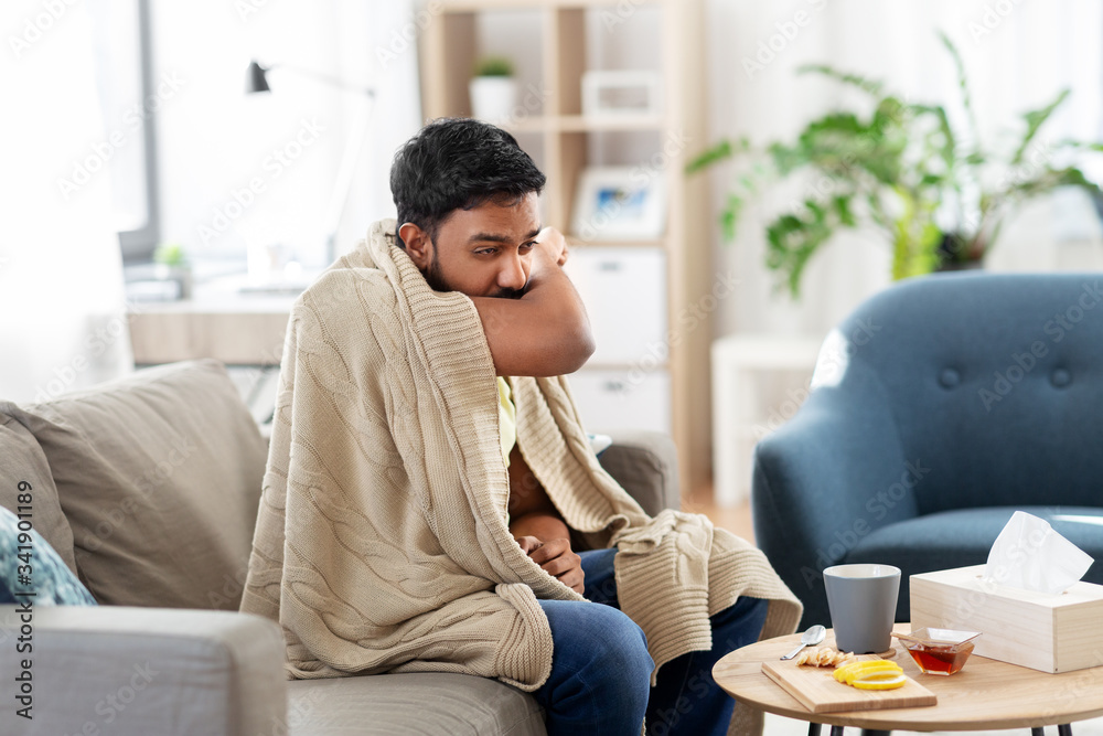 health, cold and people concept - sick young indian man in blanket coughing at home health, cold and people concept - sick young indian man in blanket coughing at home