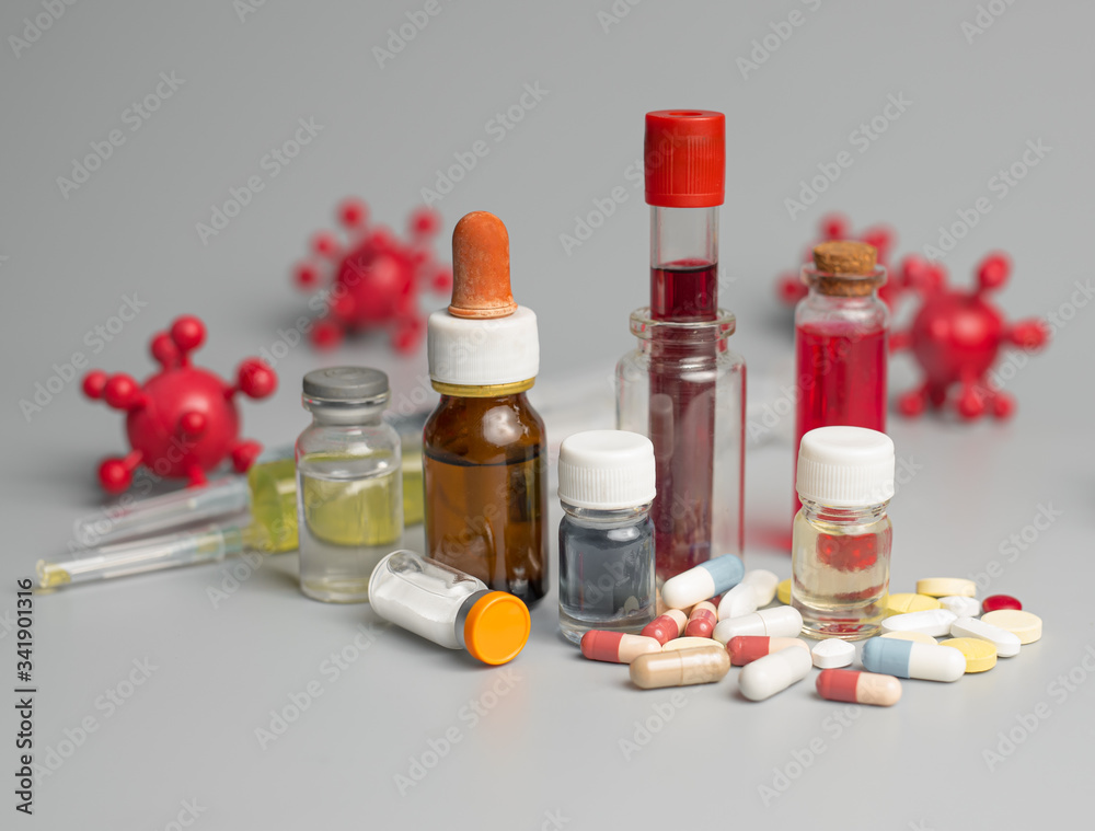 Medicine. Coronavirus (COVID-19) vaccine,Flu COVID-19 virus cell with medical glass vials and syringe on a gray background. Medicine. Coronavirus (COVID-19) vaccine,Flu COVID-19 virus cell with medical glass vials and syringe on a gray background.