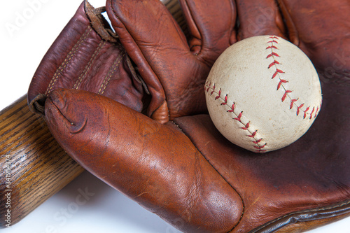A close up of a Leather baseball glove, ball an wooden bat 