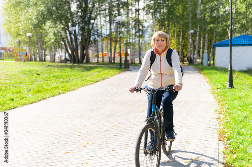 A woman on a Bicycle rides on the road in the city Park