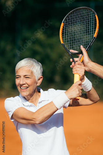 Tennis Instructor Teaching Elderly Woman How to Play Tennis © Microgen