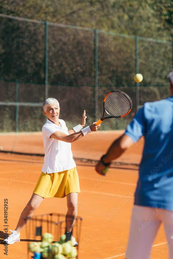 Older Woman Practicing Tennis with Instructor Older Woman Practicing Tennis with Instructor