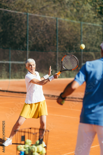 Older Woman Practicing Tennis with Instructor