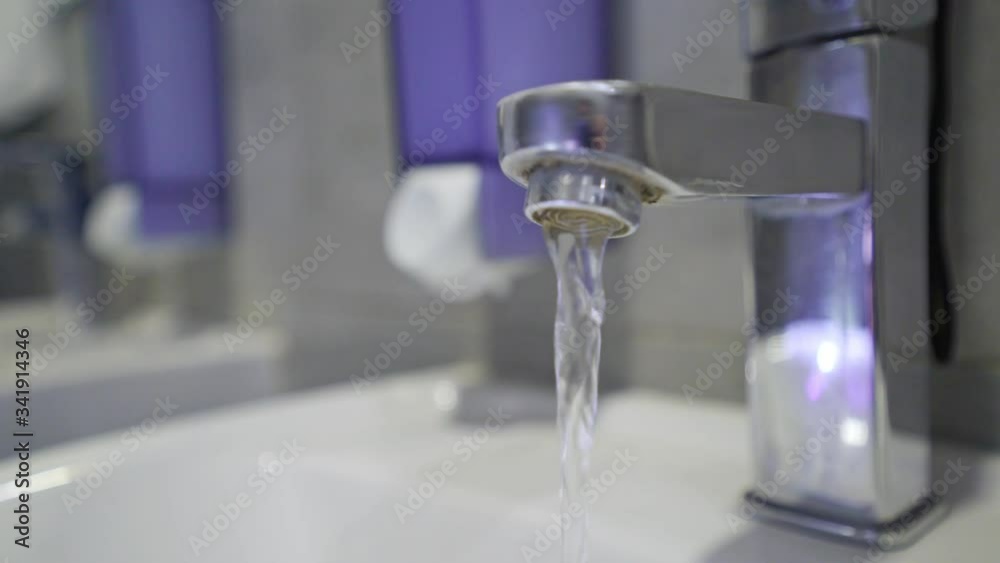 Hot tap water. Warm water flows from the tap in the bathroom. Coronavirus travel prevention washing hands with soap and hot water. Hand hygiene for coronavirus outbreak. Protection by washing hands. Hot tap water. Warm water flows from the tap in the bathroom. Coronavirus travel prevention washing hands with soap and hot water. Hand hygiene for coronavirus outbreak. Protection by washing hands.