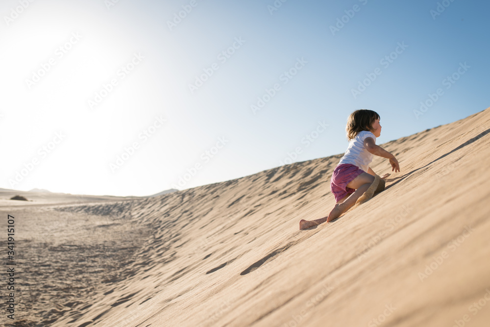 Little girl climbing up sand dunes