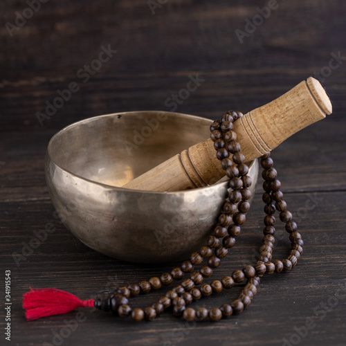 Mala beads and tibetan singing bowl on wooden square background.  Mindfulness or meditation concept. photo