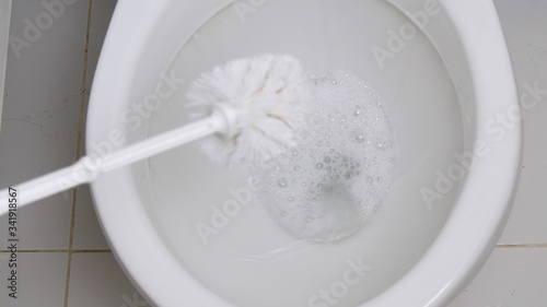 A Person with Protection Clothes and Gloves in Hands Disinfecting Toilet Bowl in Bathroom Using a Toilet Brush