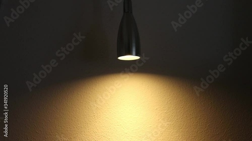 A dimmable light in a dark room and its effect on a wall. The brightness of the light increases and decreases. The dimmer is set on a small led light photo