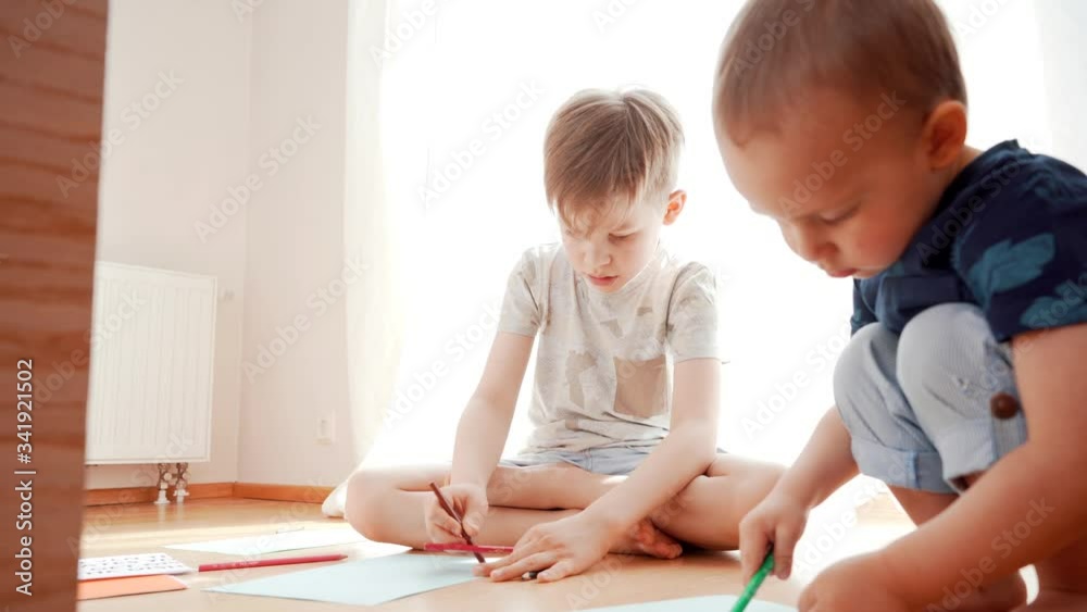 Two happy kids drawing, writing and learning. Small brothers having fun together. Family unity and home education concept. Two happy kids drawing, writing and learning. Small brothers having fun together. Family unity and home education concept.