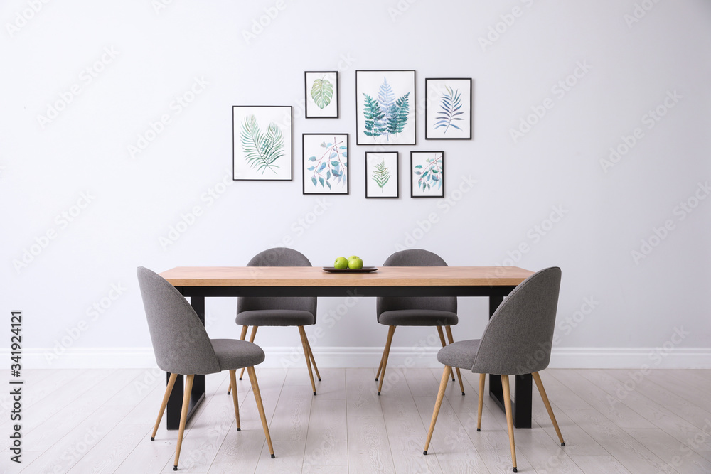 Stylish room interior with modern table, chairs and paintings of tropical leaves. Idea for design Stylish room interior with modern table, chairs and paintings of tropical leaves. Idea for design