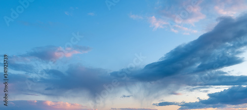 storm clouds illuminated by the setting sun and rain in the distance. blue sky. Background