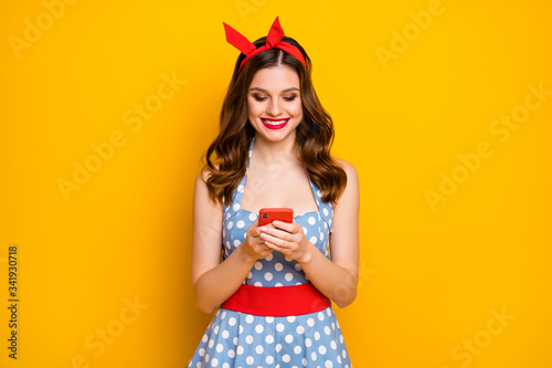 Portrait of positive cheerful girl use smartphone read social media feedback news enjoy wear vintage style dress isolated over bright shine color background