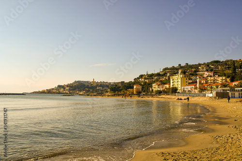 Fototapeta Naklejka Na Ścianę i Meble -  Scenic view of the beach with the Sanctuary of the Sacred Heart of Bussana and Capo dell'Arma cape in the background in a sunny winter day, Arma di Taggia, Imperia, Liguria, Italy